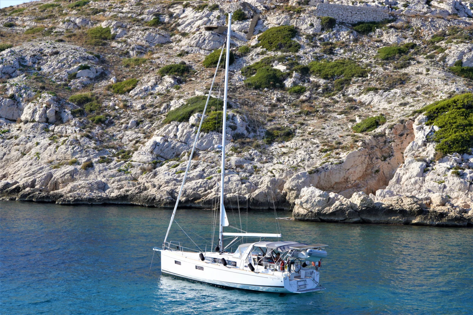Barca a vela all’ancora sotto una costa rocciosa